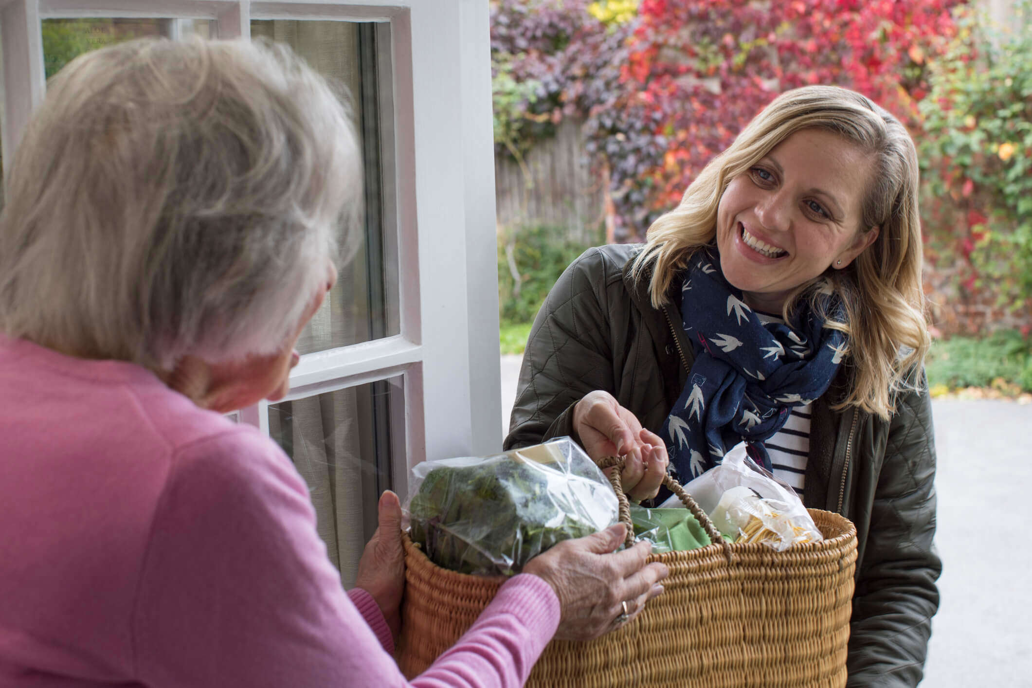 A woman deliverying some shopping to an older woman