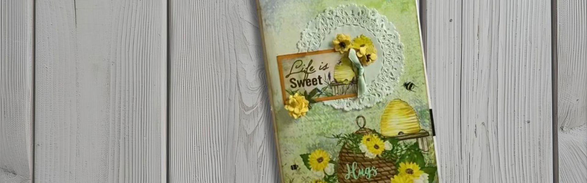 Main image: a DIY pencil case/stationery pouch, made using upcycled junk mail, ribbons and fake flowers. With a beehive and 'life is sweet' moto.