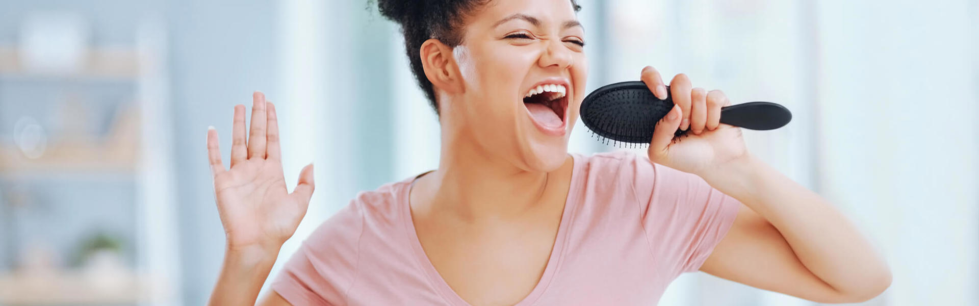 A woman singing into a hair brush