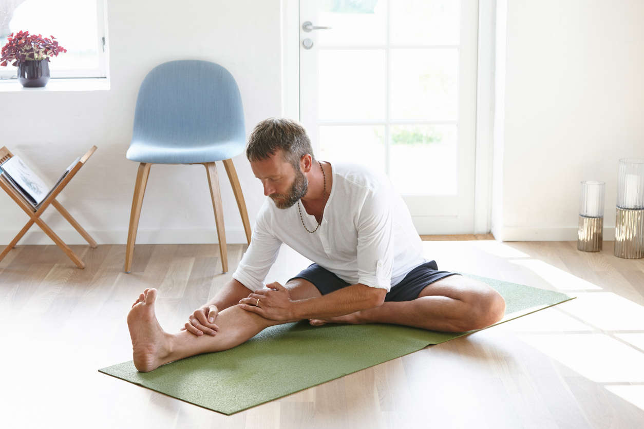 a man stretching on a green yoga mat 