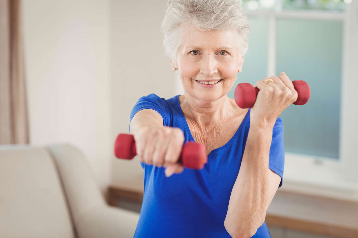 a woman wearing a blue exercise top holding red hand weights