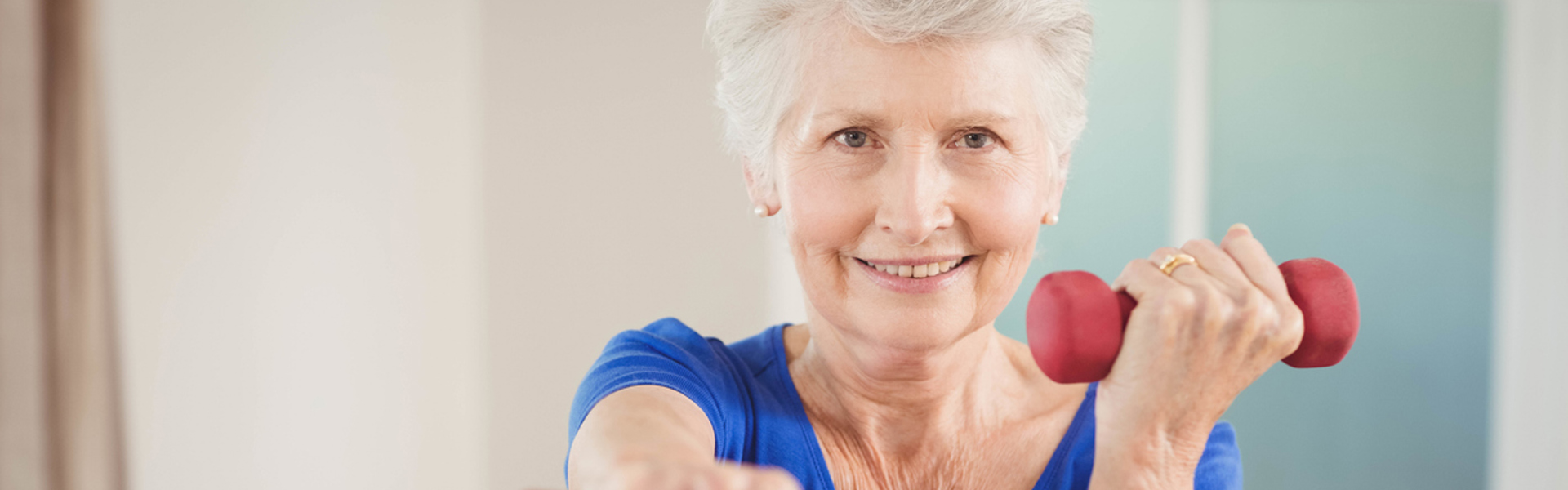 a woman wearing a blue exercise top holding red hand weights