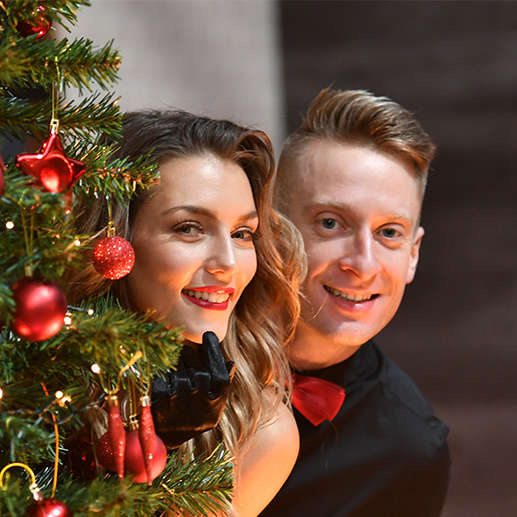 Dance duo Michael and Jowita peaking out form behind a christmas tree