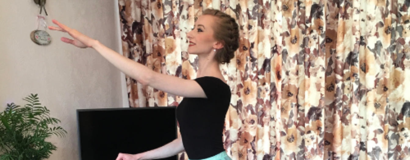 Photo of Johanna Hadley, Silver Swans® Ballet Instructor from the Royal Academy of Dance, in her living room holding a ballet pose, in a beautiful blue ballet skirt.