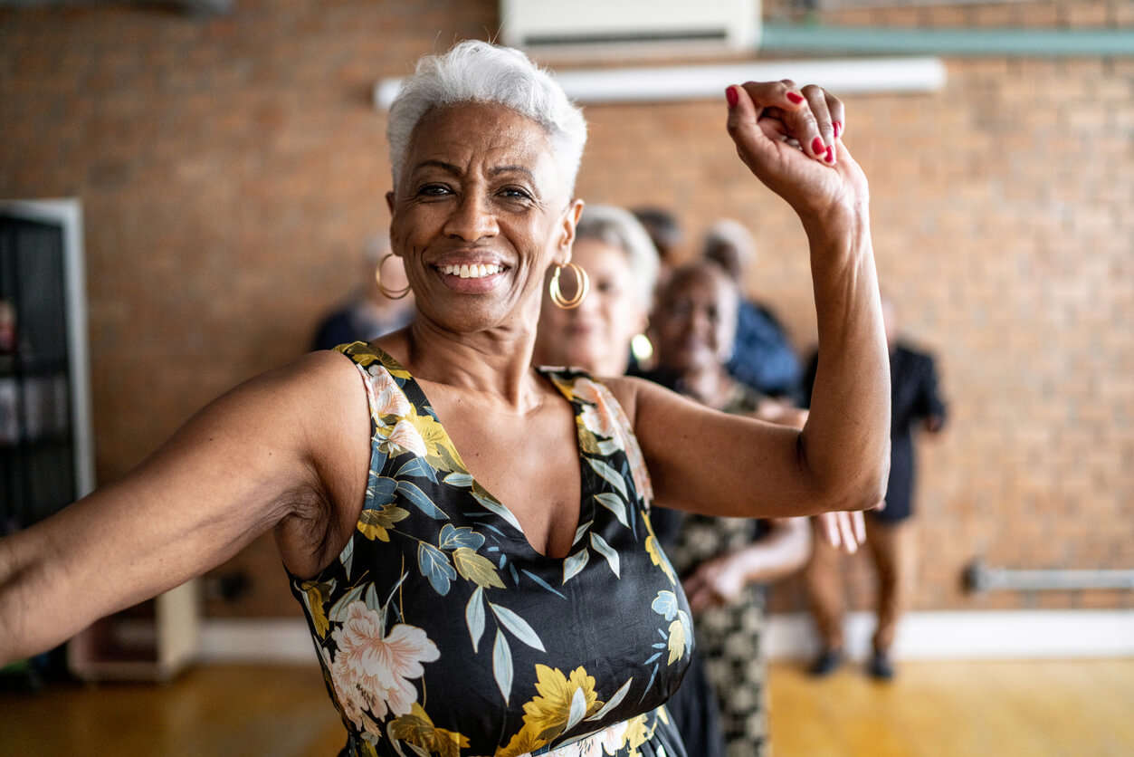 Lady in a black floral dress dancing in a class, with other dancers in the background