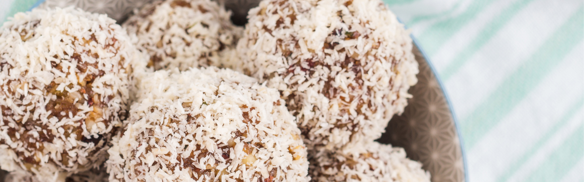 No Bake Date Energy Balls in a bowl on a white and green striped table cloth.