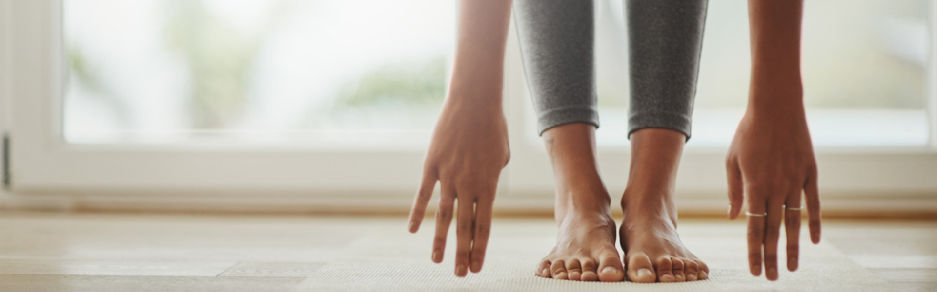 Main image: a woman doing a Pilates for heart health with class with April, reaching for her toes on a yoga mat.