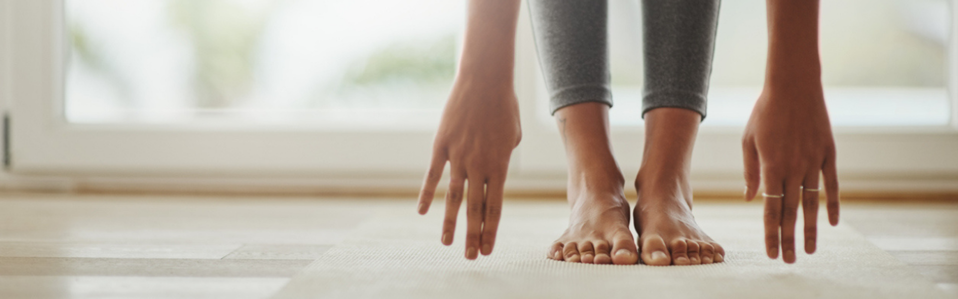 Main image: a woman doing a Pilates for heart health with class with April, reaching for her toes on a yoga mat.