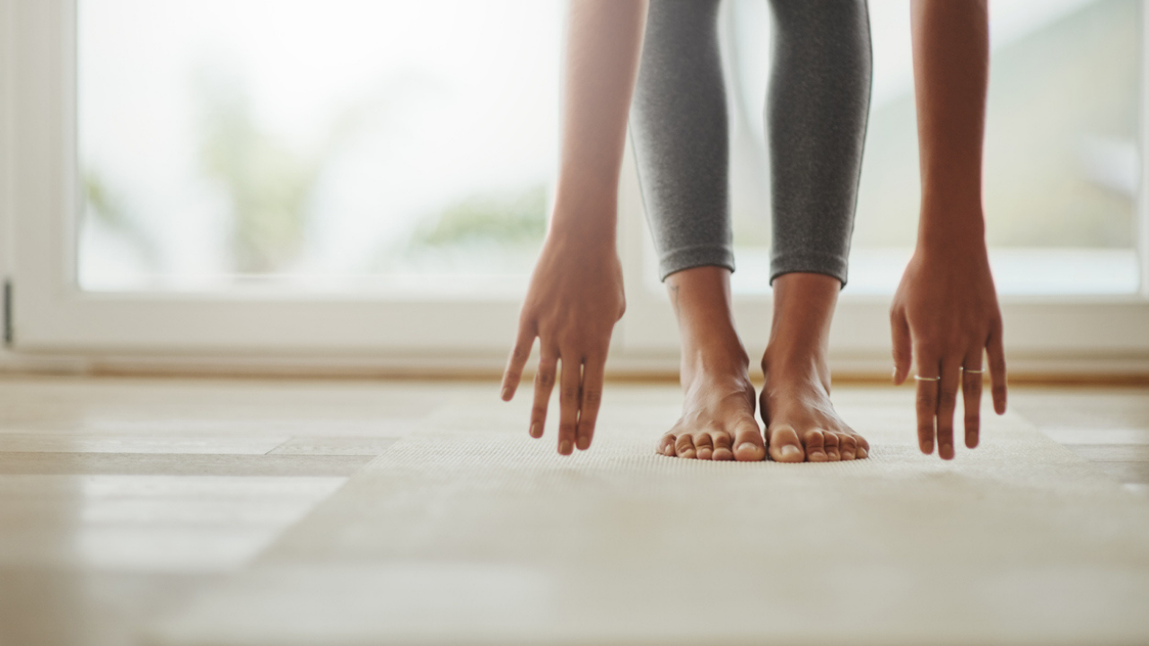 Main image: a woman doing a Pilates for heart health with class with April, reaching for her toes on a yoga mat.