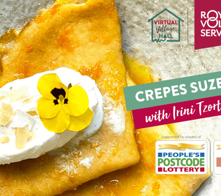 fresh homemade Crepes Suzette on a plate decorated with a scoop of white vanilla ice cream, maple syrup and a small yellow flower