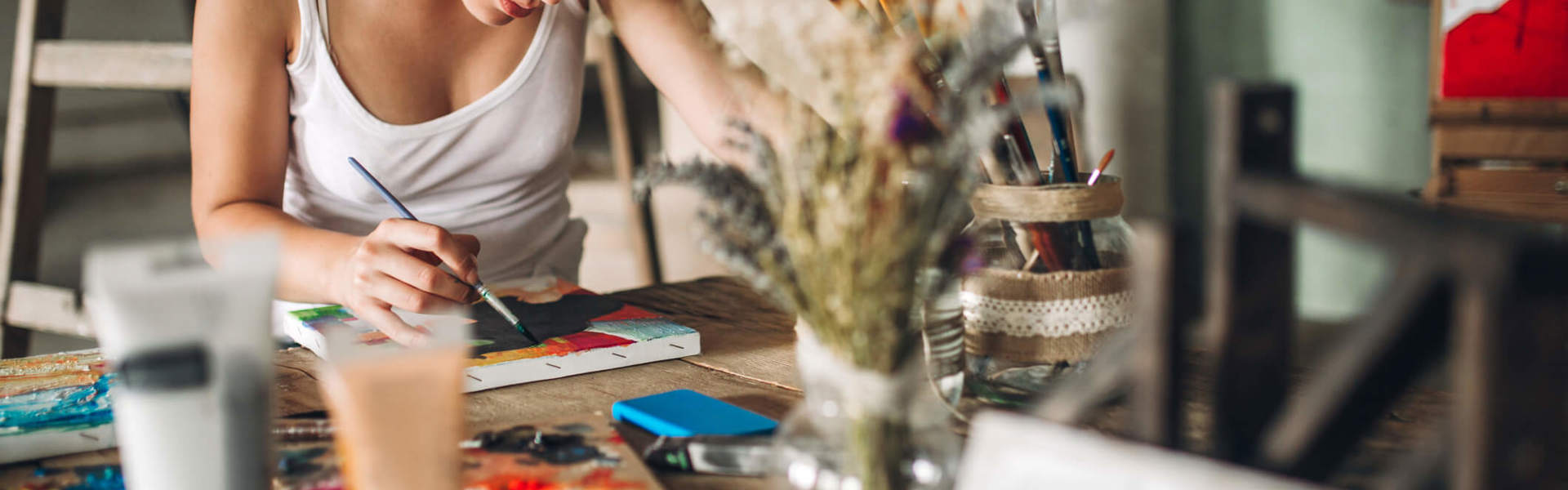 a woman sat a table painting in an art studio