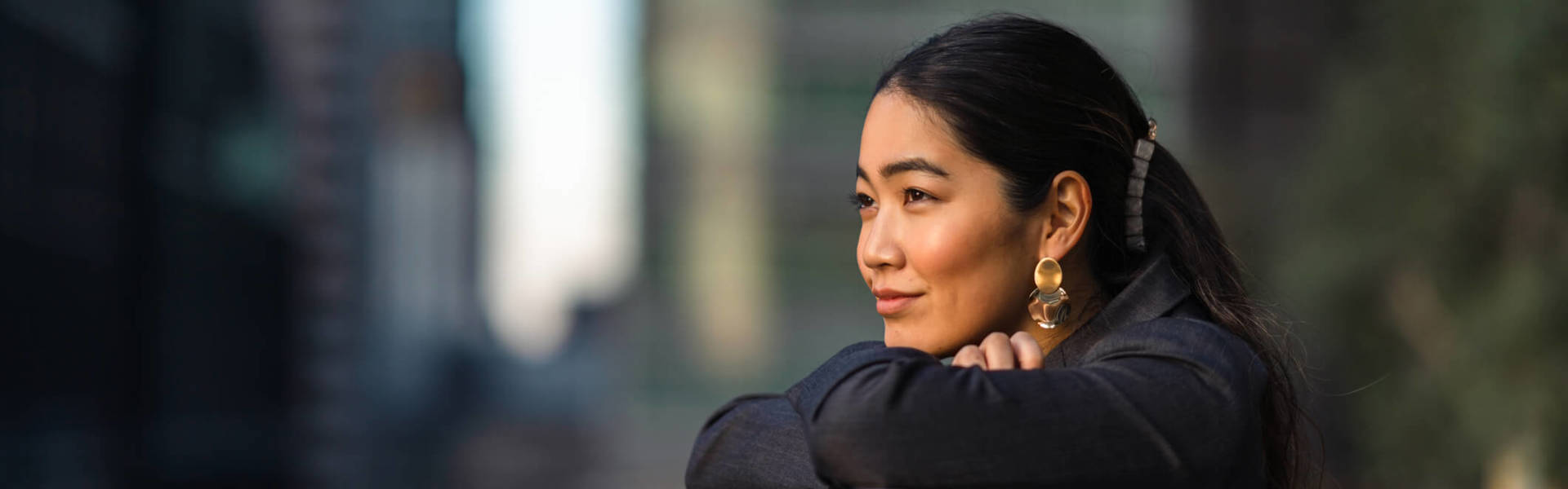Portrait of a woman with her chin resting on her arms crossed looking out over a balcony