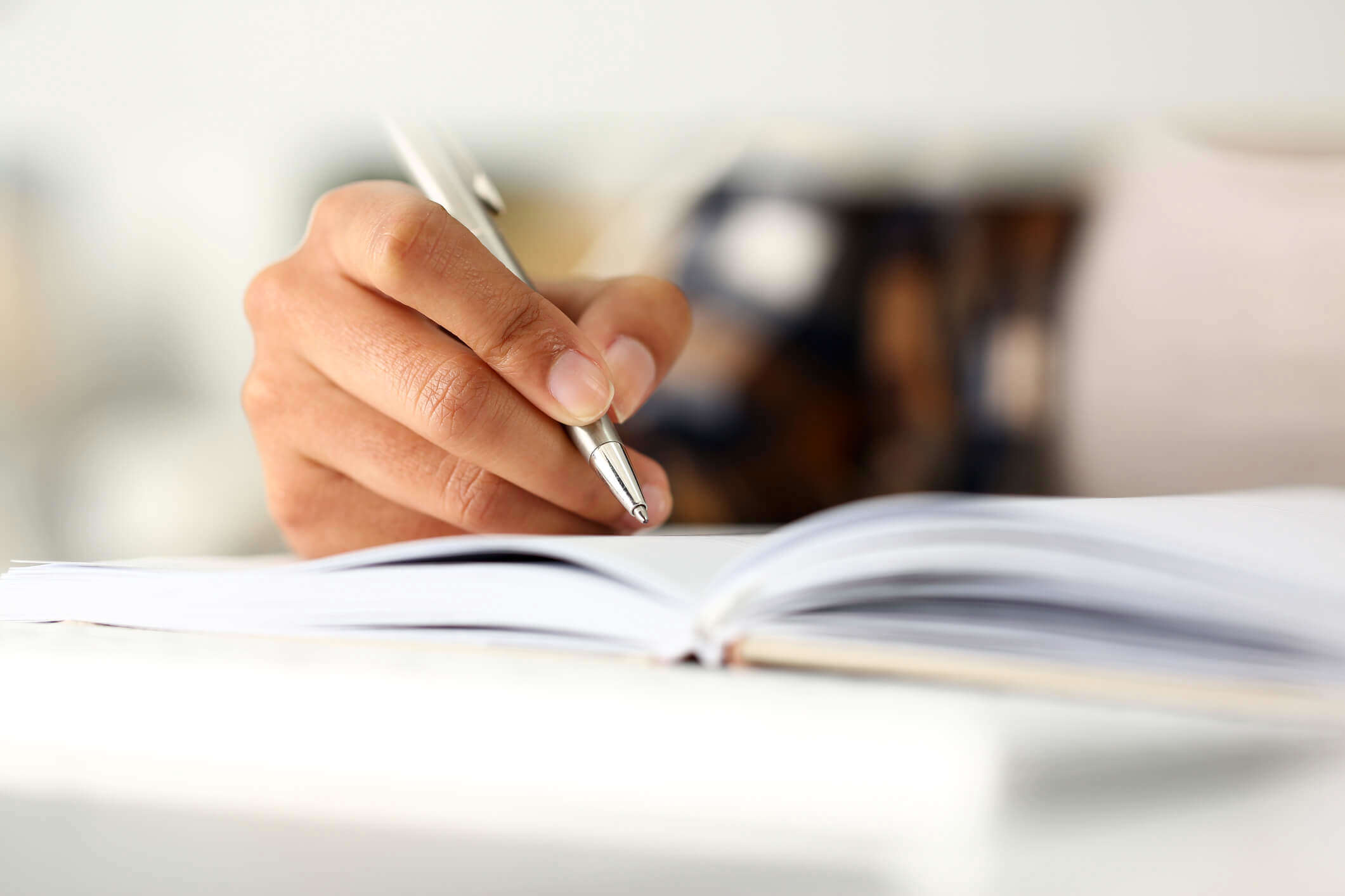 a close up of someone holding a pen and writing in a journal