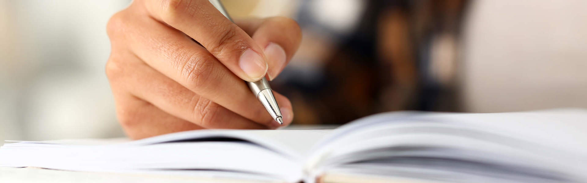 a close up of someone holding a pen and writing in a journal