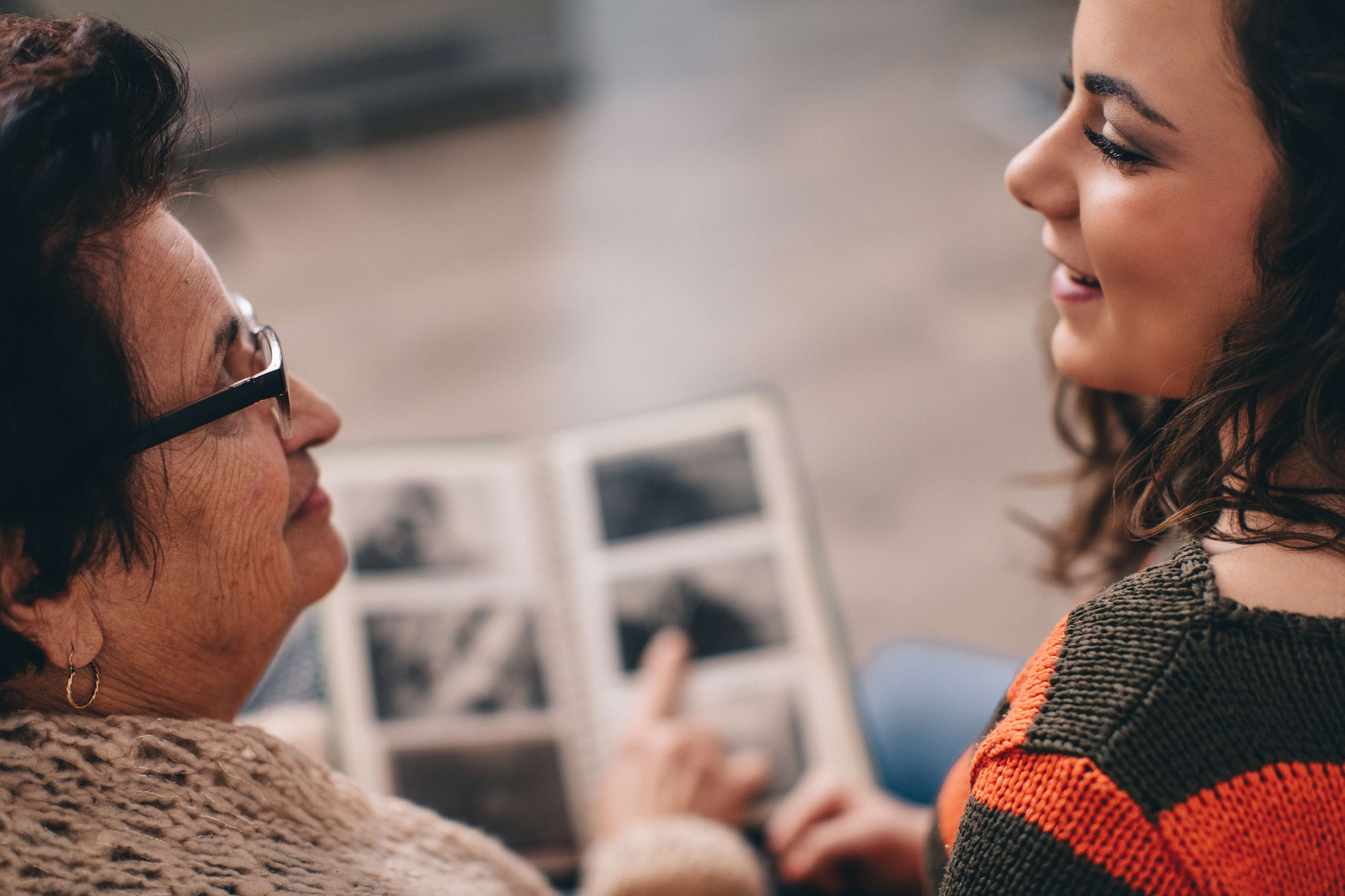 Main Image: two people sat looking at a photo album together, smiling.