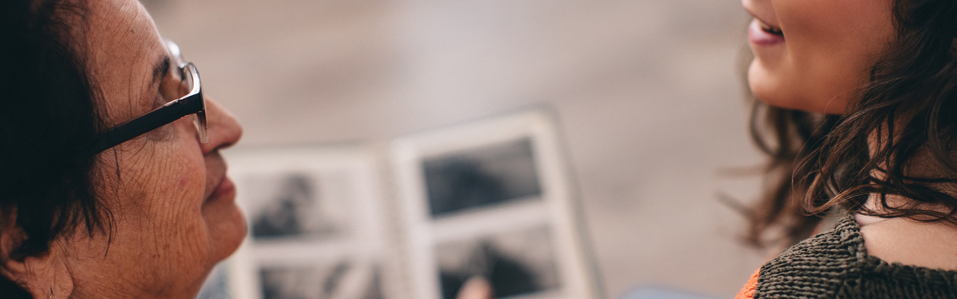 Main Image: two people sat looking at a photo album together, smiling.