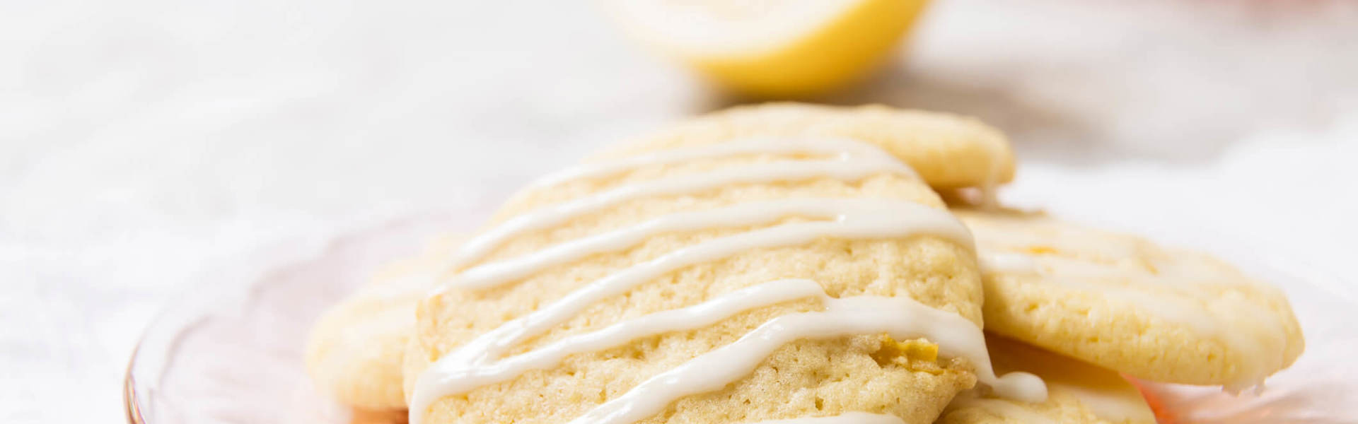 lemon shortcake biscuits topped with white zigzag icing on a pink plate