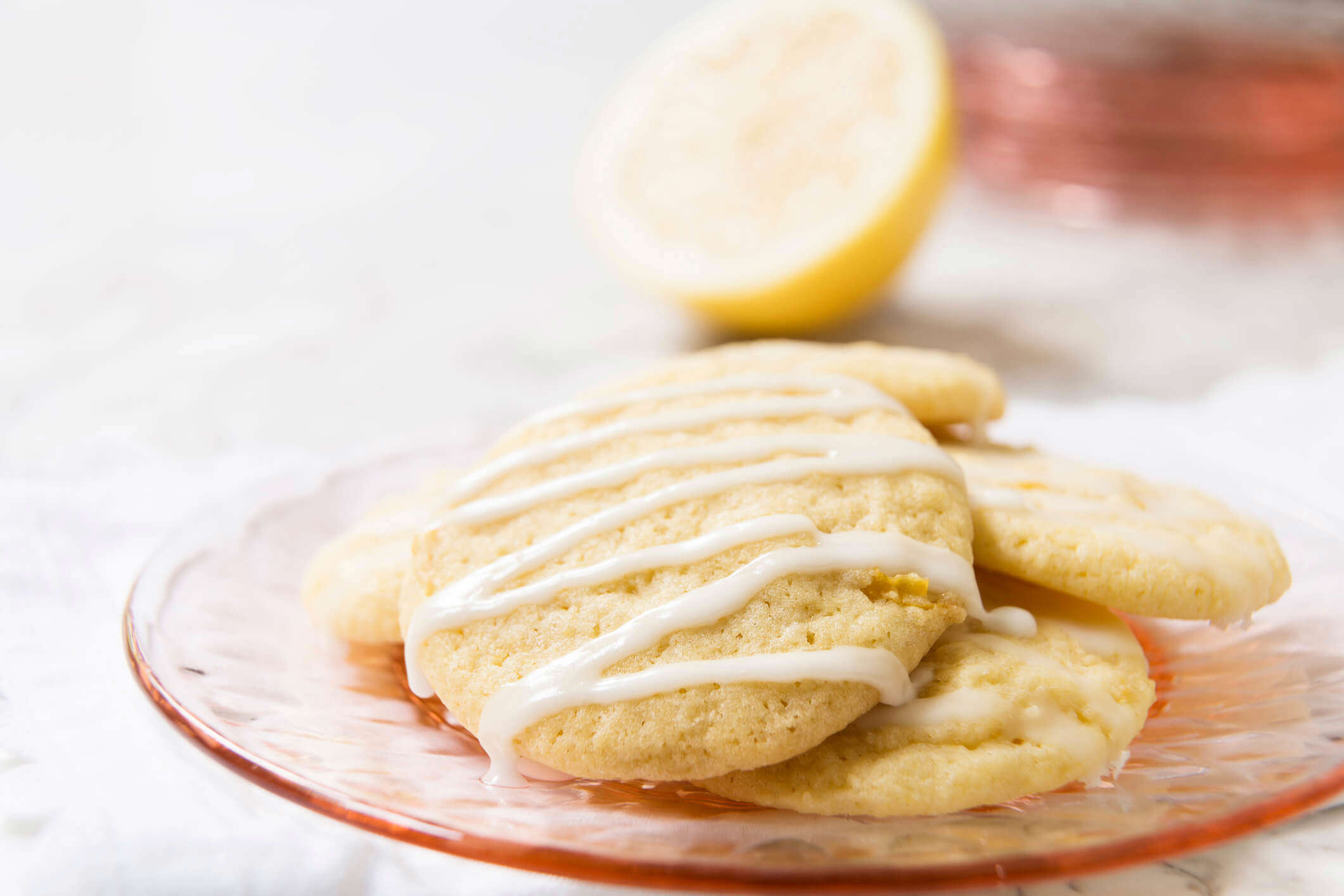 lemon shortcake biscuits topped with white zigzag icing on a pink plate