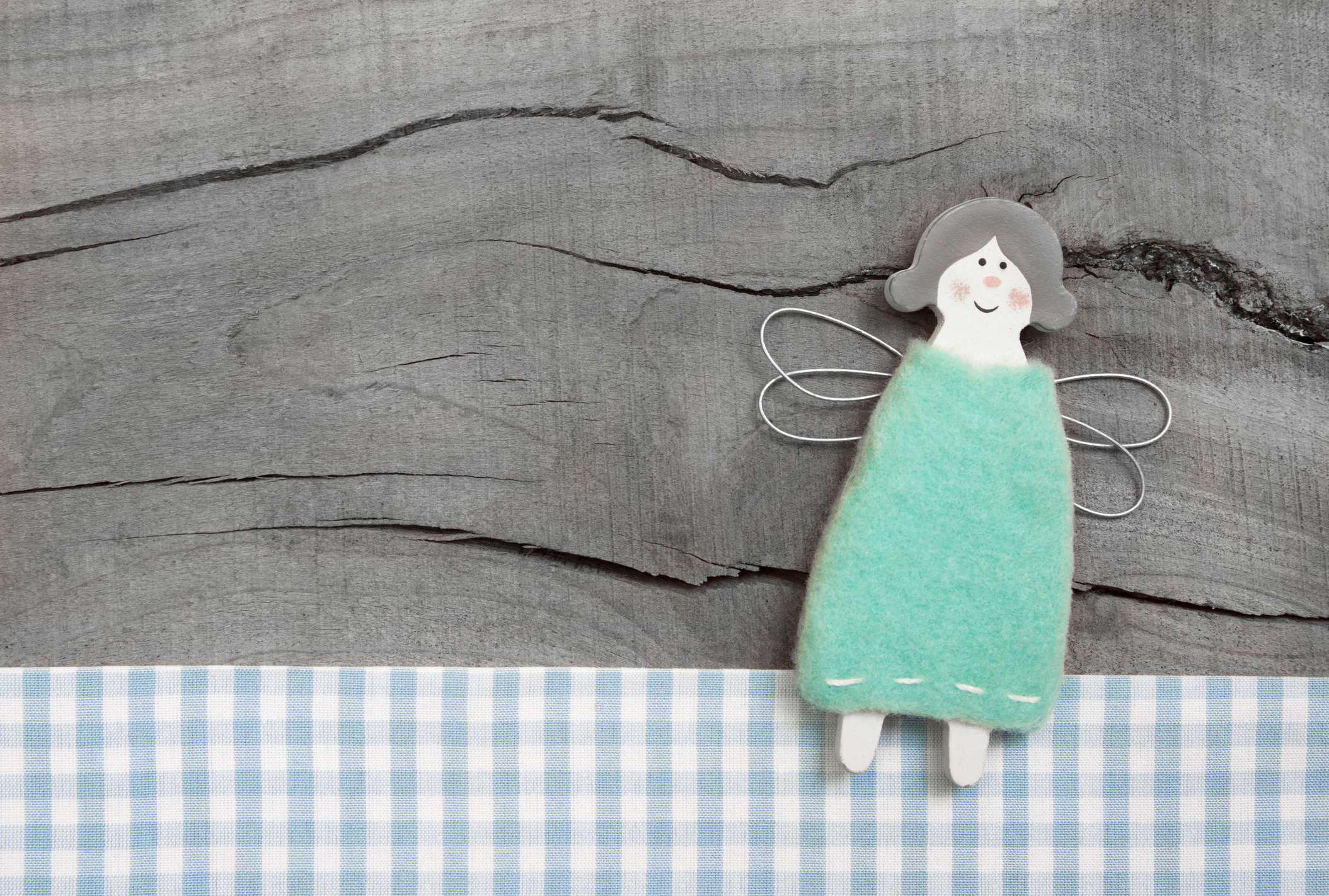 a DIY handmade blue peg doll fairy resting on a wooden table