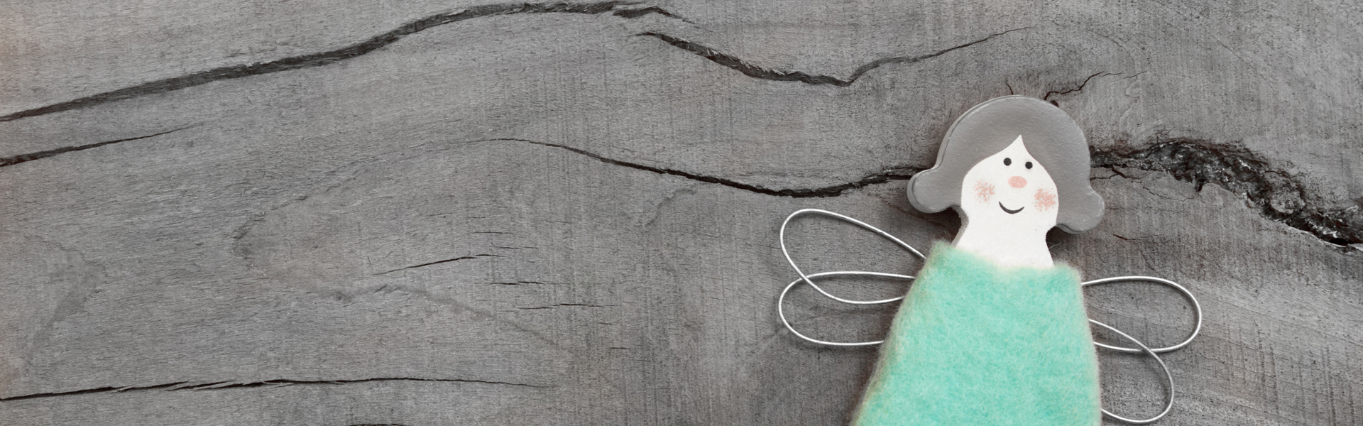 a DIY handmade blue peg doll fairy resting on a wooden table
