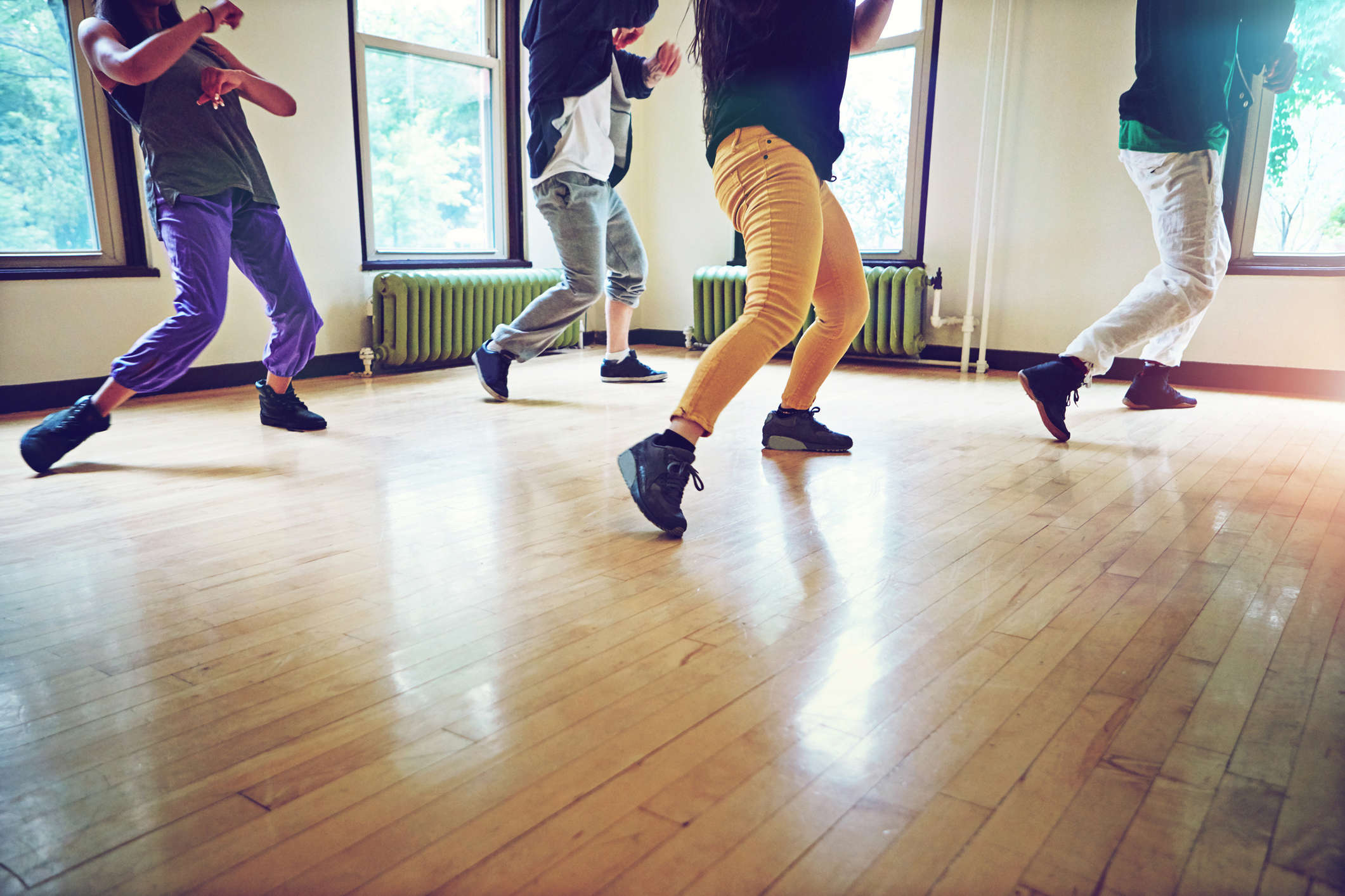 Photo of 4 people dancing in a class, with the image cut off at their shoulders.