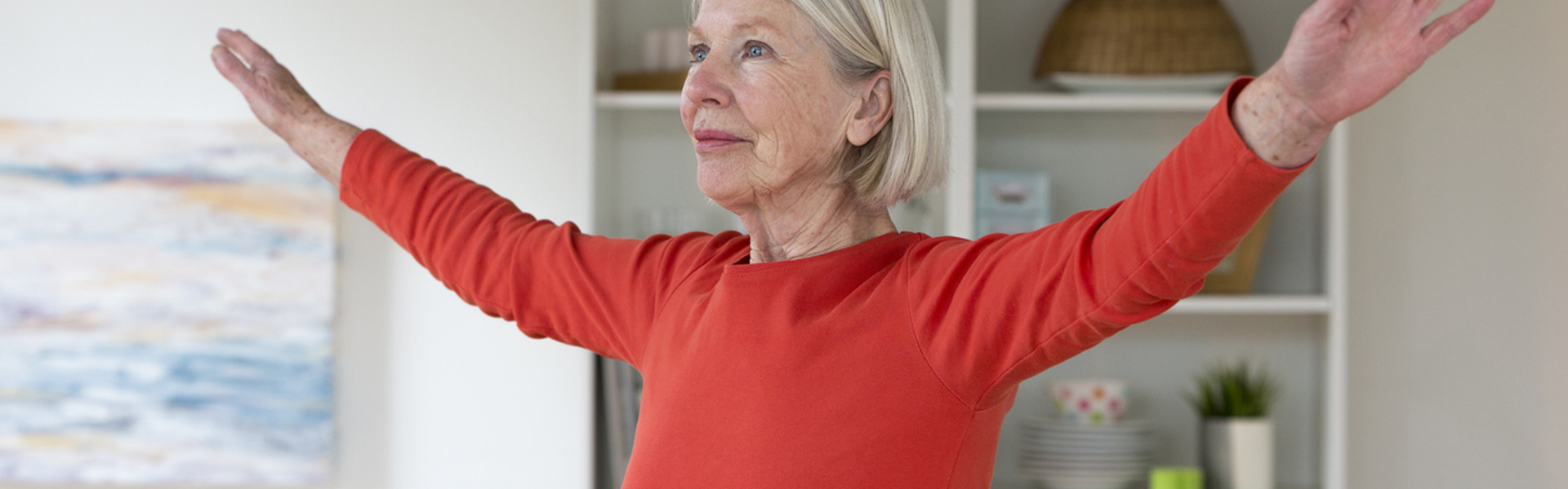 a woman wearing a red top doing a stretch in her living room at home