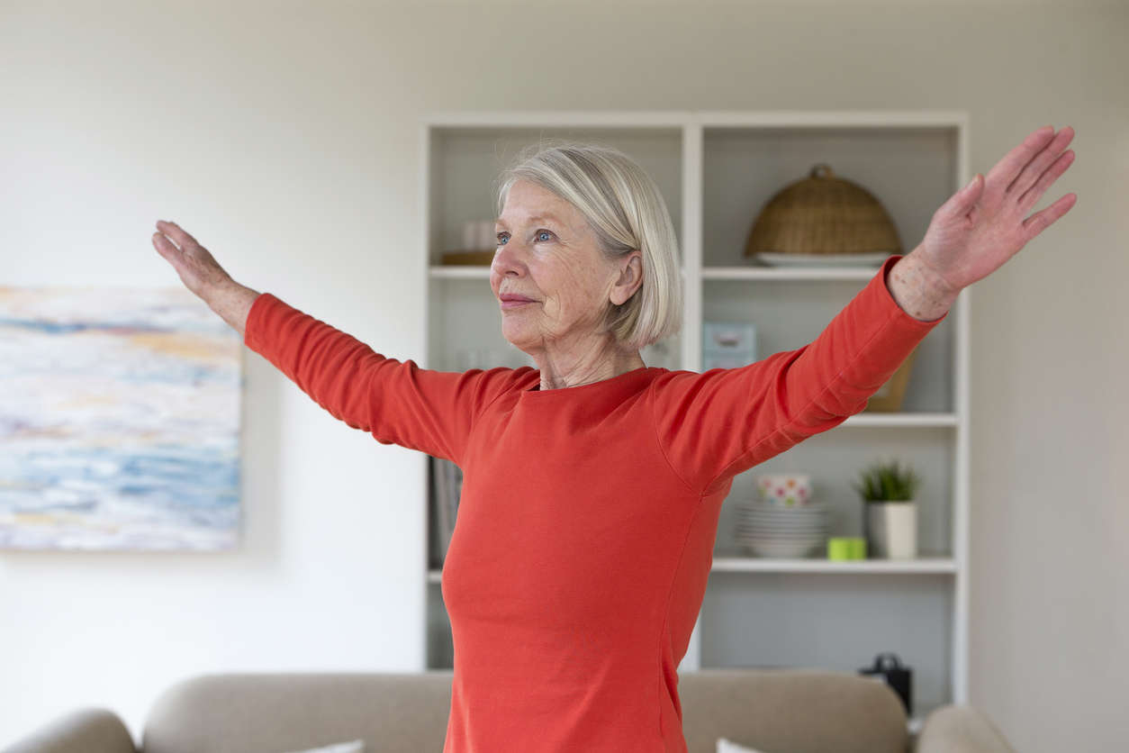 a woman wearing a red top doing a stretch in her living room at home