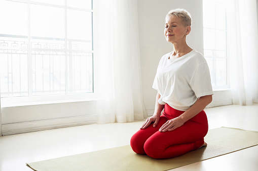 a woman kneeling on a yoga mat in her living room