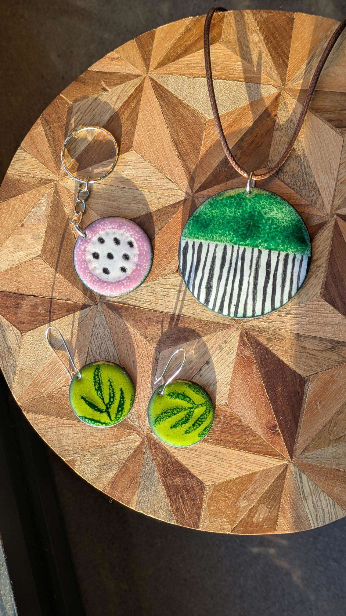 Main image: handmade enamel jewellery pendants, greens and pinks, with various patterns. 