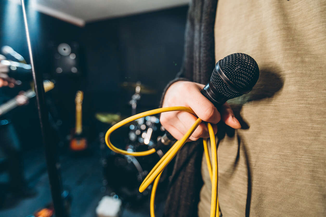 a hand holding a microphone with a yellow cord coming out of it