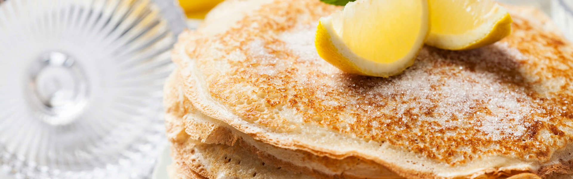 a stack of homemade pancakes covered with sugar and topped with lemon slices