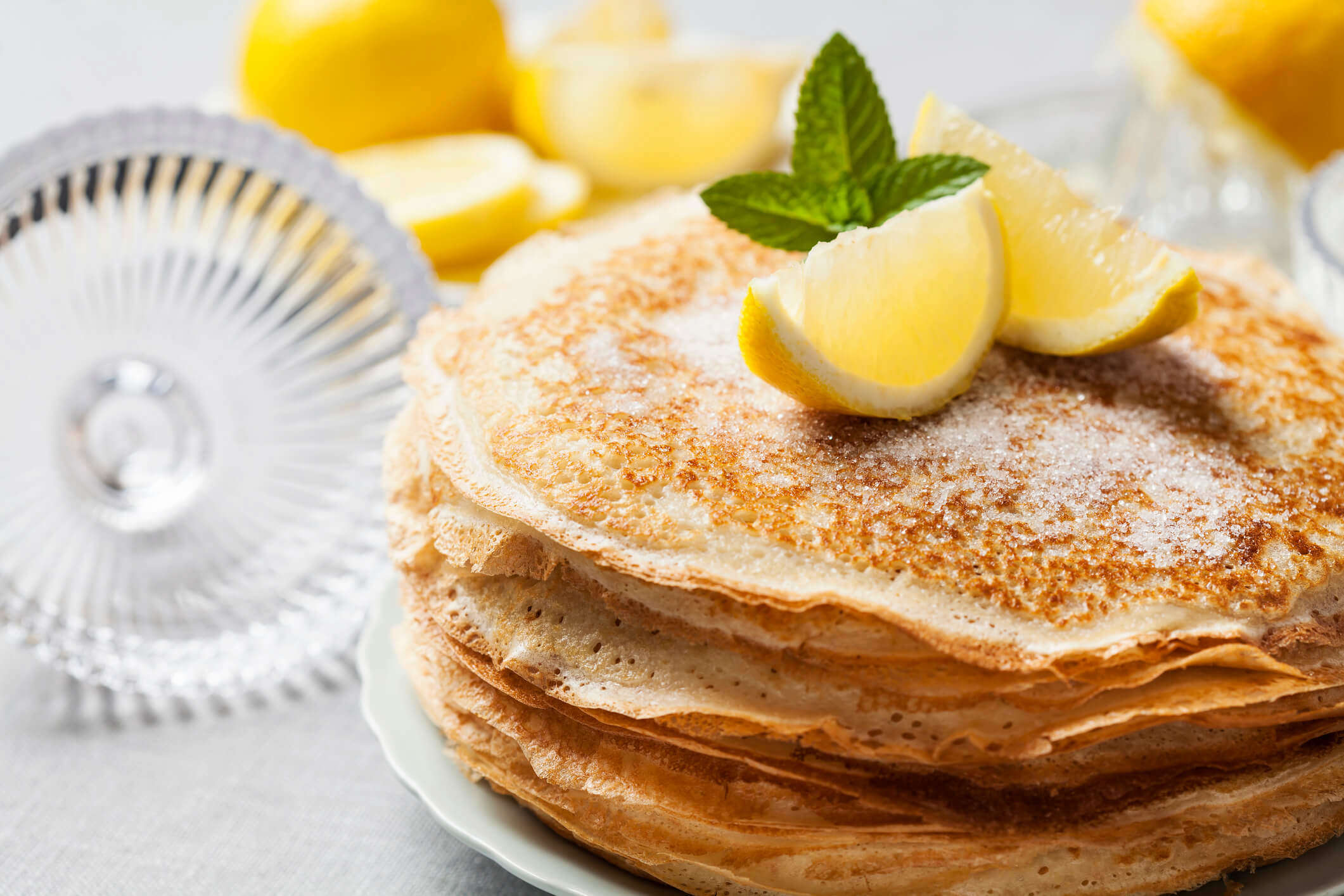 a stack of homemade pancakes covered with sugar and topped with lemon slices