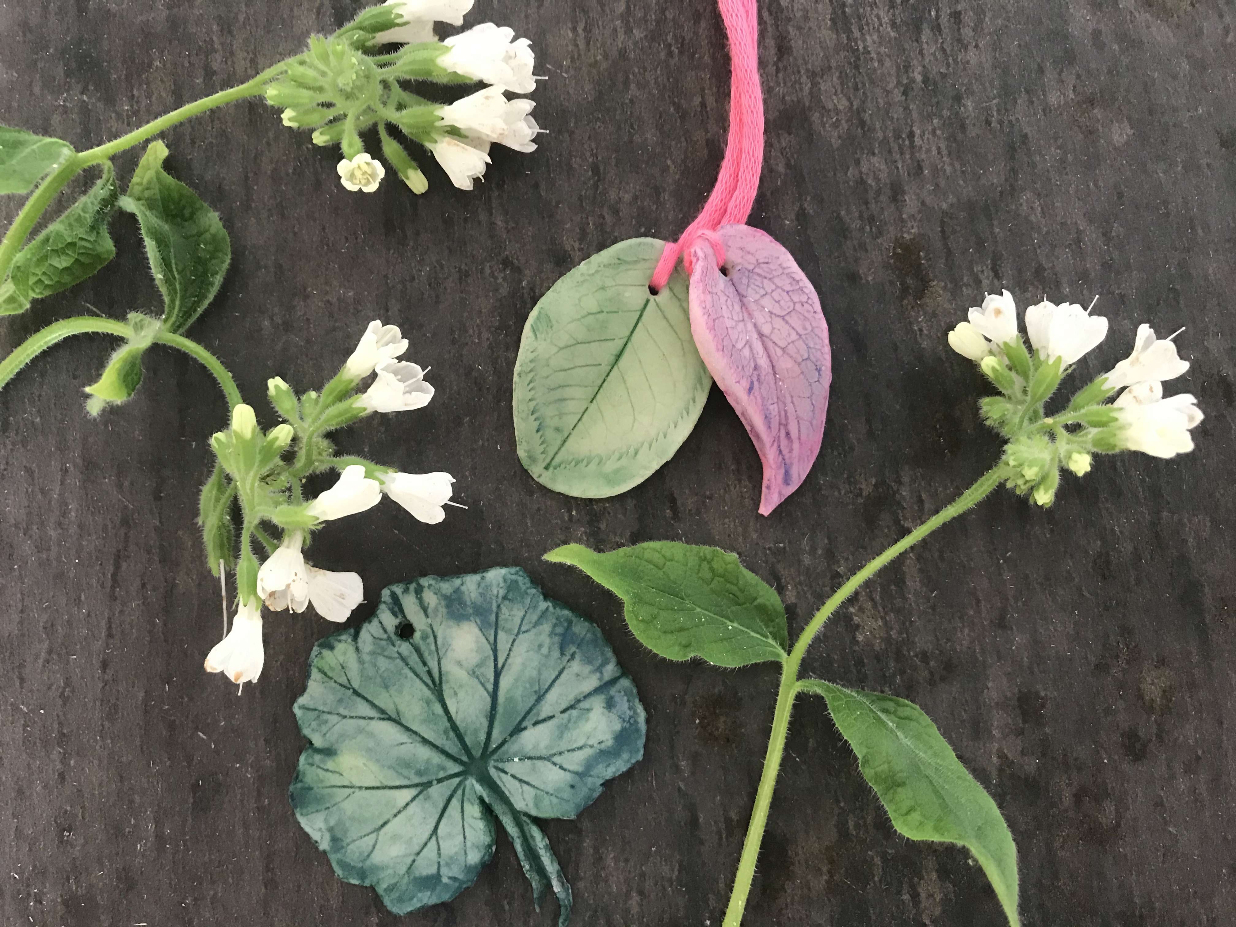 Homemade Air-Dry Clay Pendants and flowers on a black background