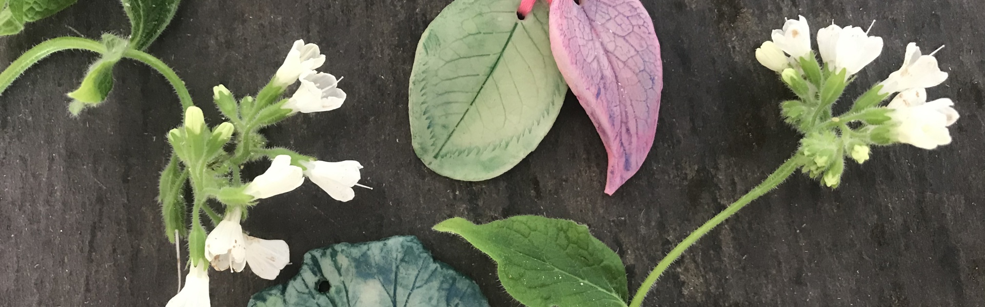 Homemade Air-Dry Clay Pendants and flowers on a black background
