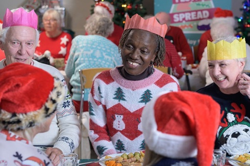 Group of people in Christmas jumpers, celebrating the festive season with a Christmas dinner together at a Royal Voluntary Service - Our Festive Spread Celebration.