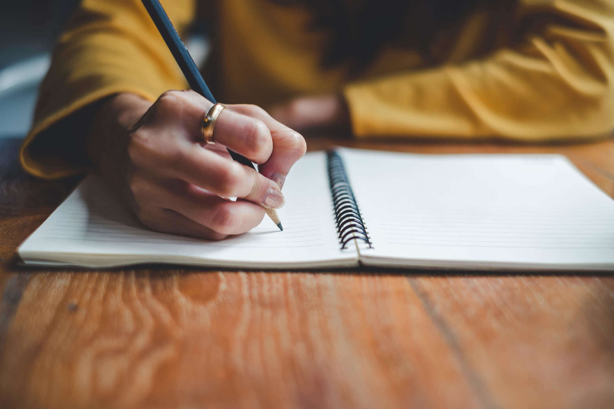 a close up of someone wearing a yellow jumper writing in a journal