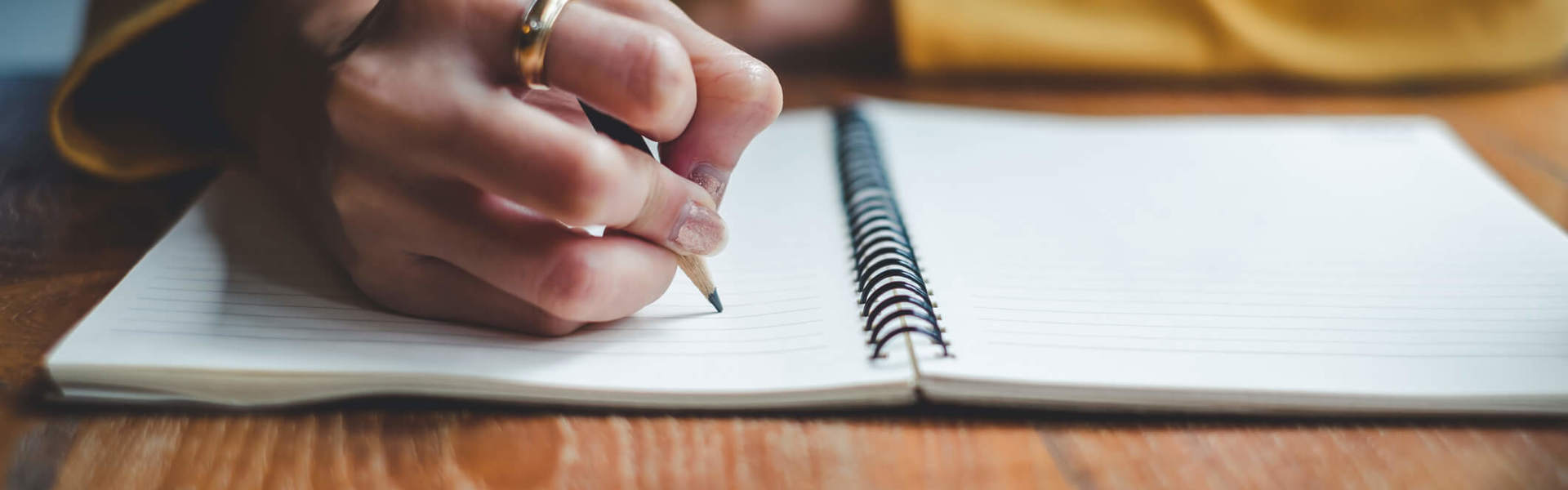 a close up of someone wearing a yellow jumper writing in a journal