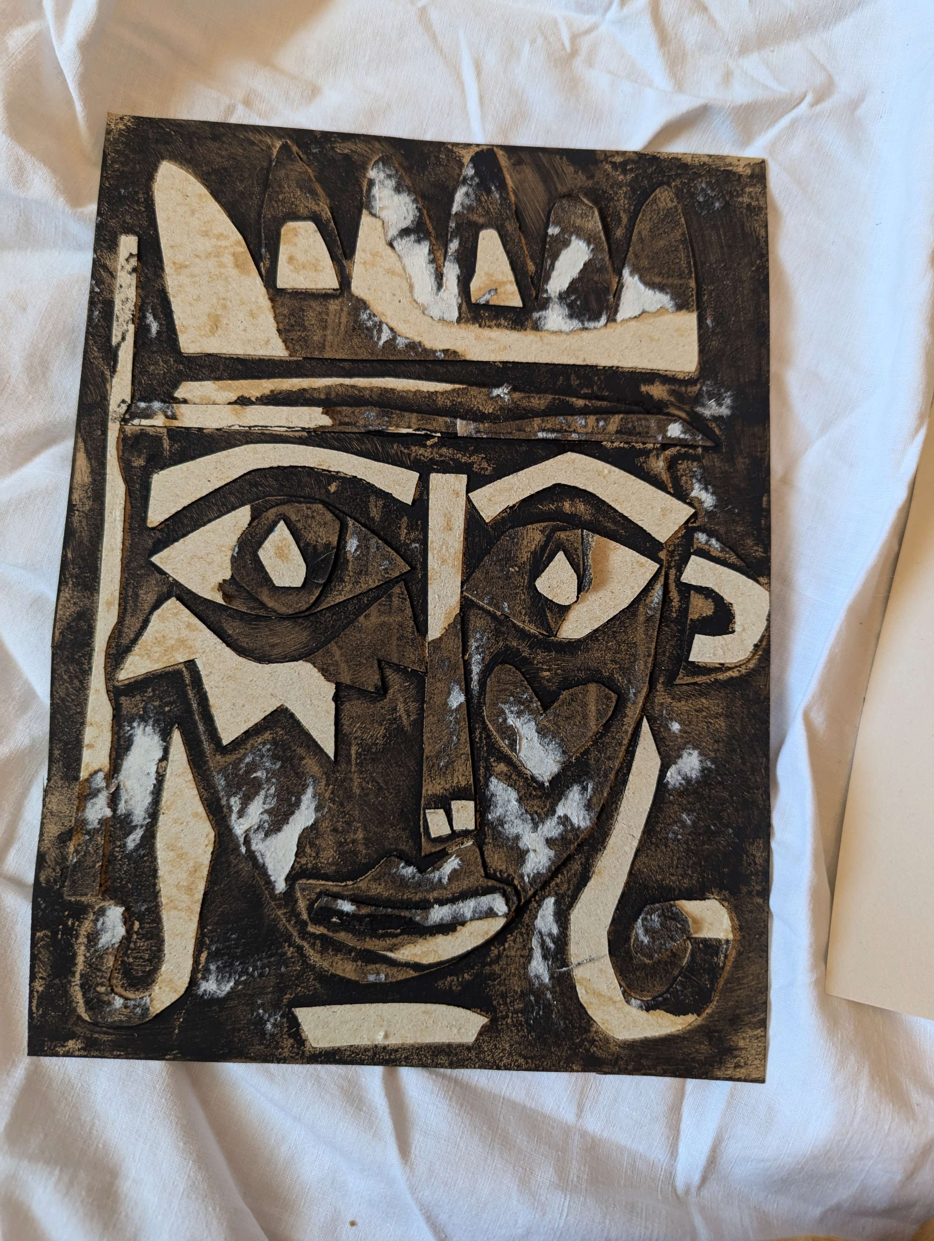 Main image: An Abstract Collage Face made from a Cereal Box - brown cardboard with details painted in black.