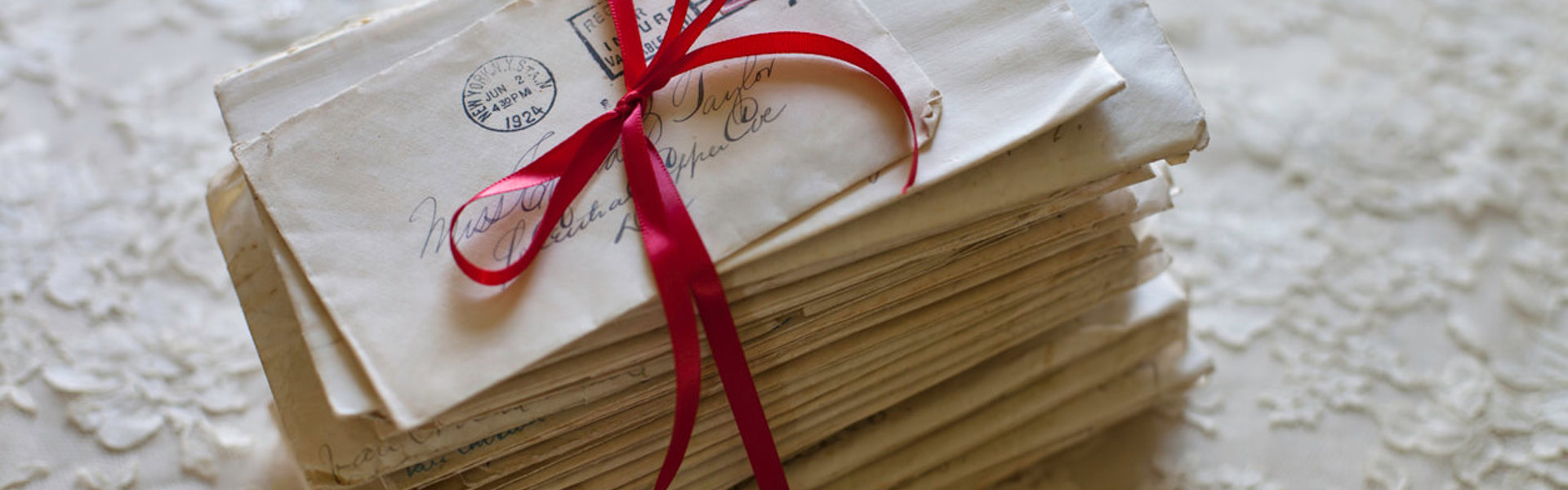 a stack of handwritten letters tied with a red bow