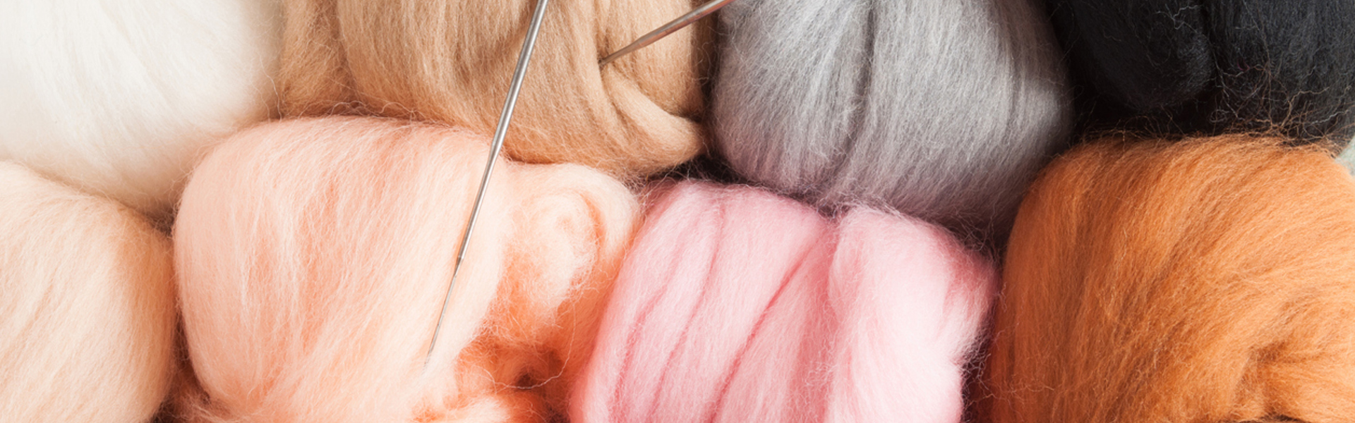 a close up of felting needles in colourful balls of felt