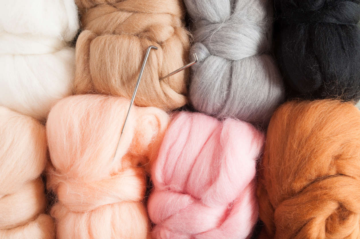 a close up of felting needles in colourful balls of felt