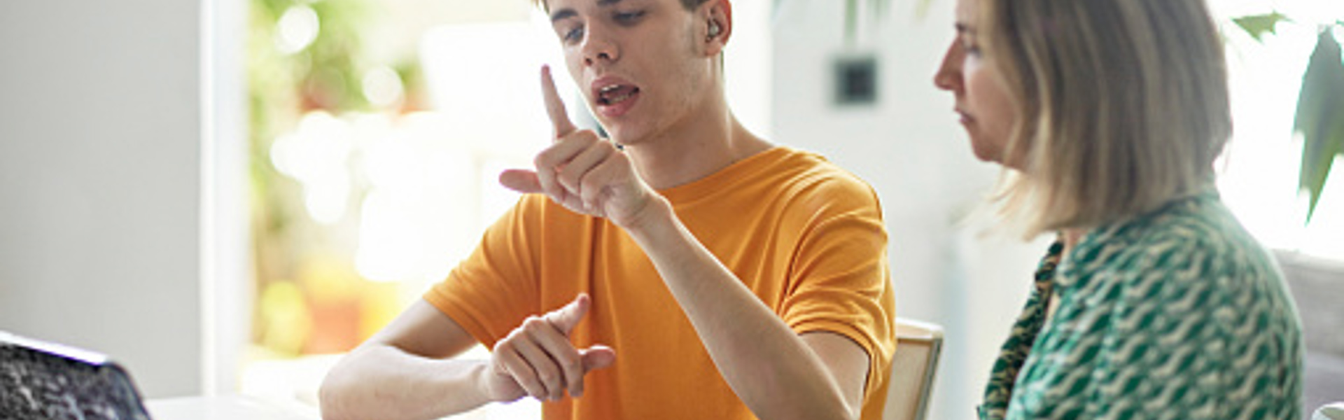 a woman and a boy learning sign language from a laptop