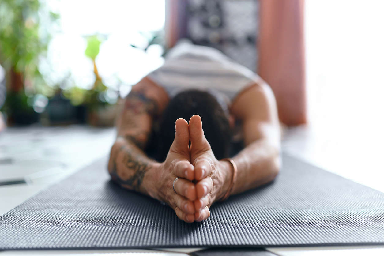 a picture of a man on a yoga mat with his hands above his head lying down in prayer position