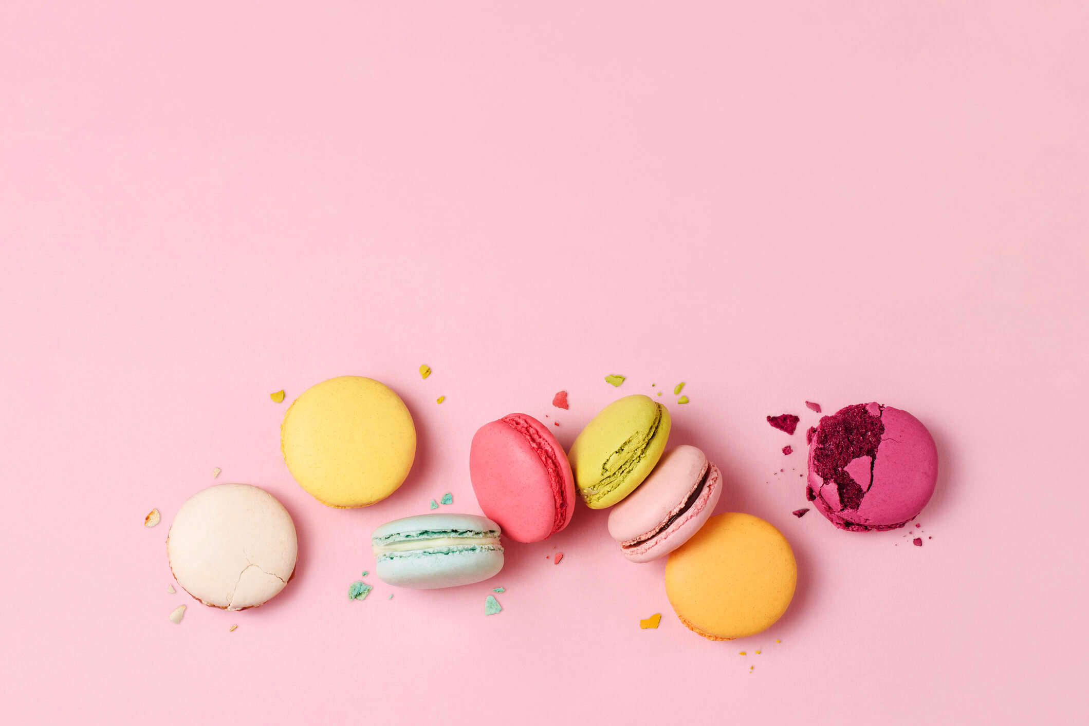 different coloured macarons on a pink background