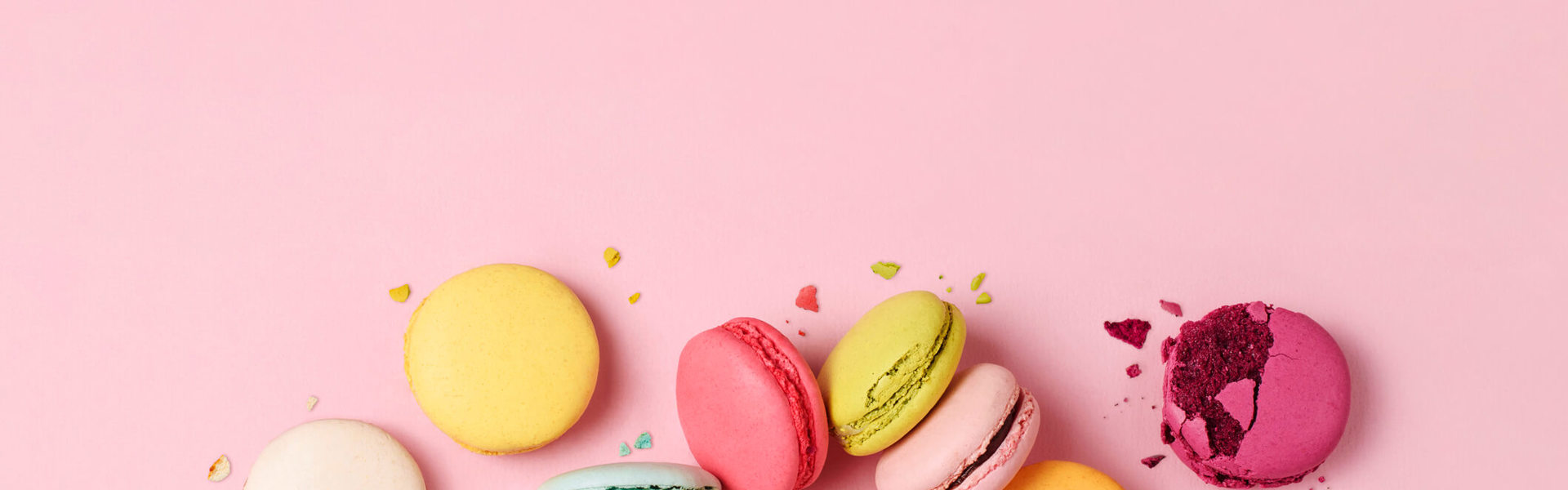 different coloured macarons on a pink background