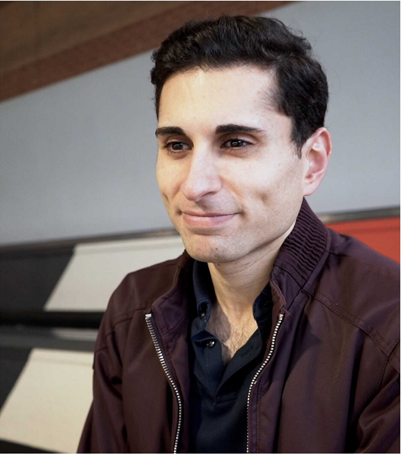Head shot photo of Dr Hussain smiling, wearing a brow jacket.