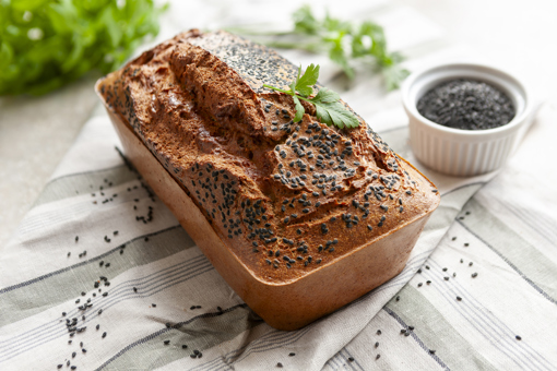 Main image: a gluten-free red lentil bread loaf, with black sesame seeds on top and a parsley sprig on top.
