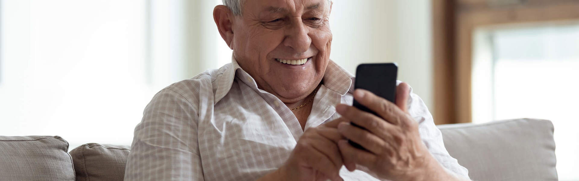 a older man looking at his phone and smiling