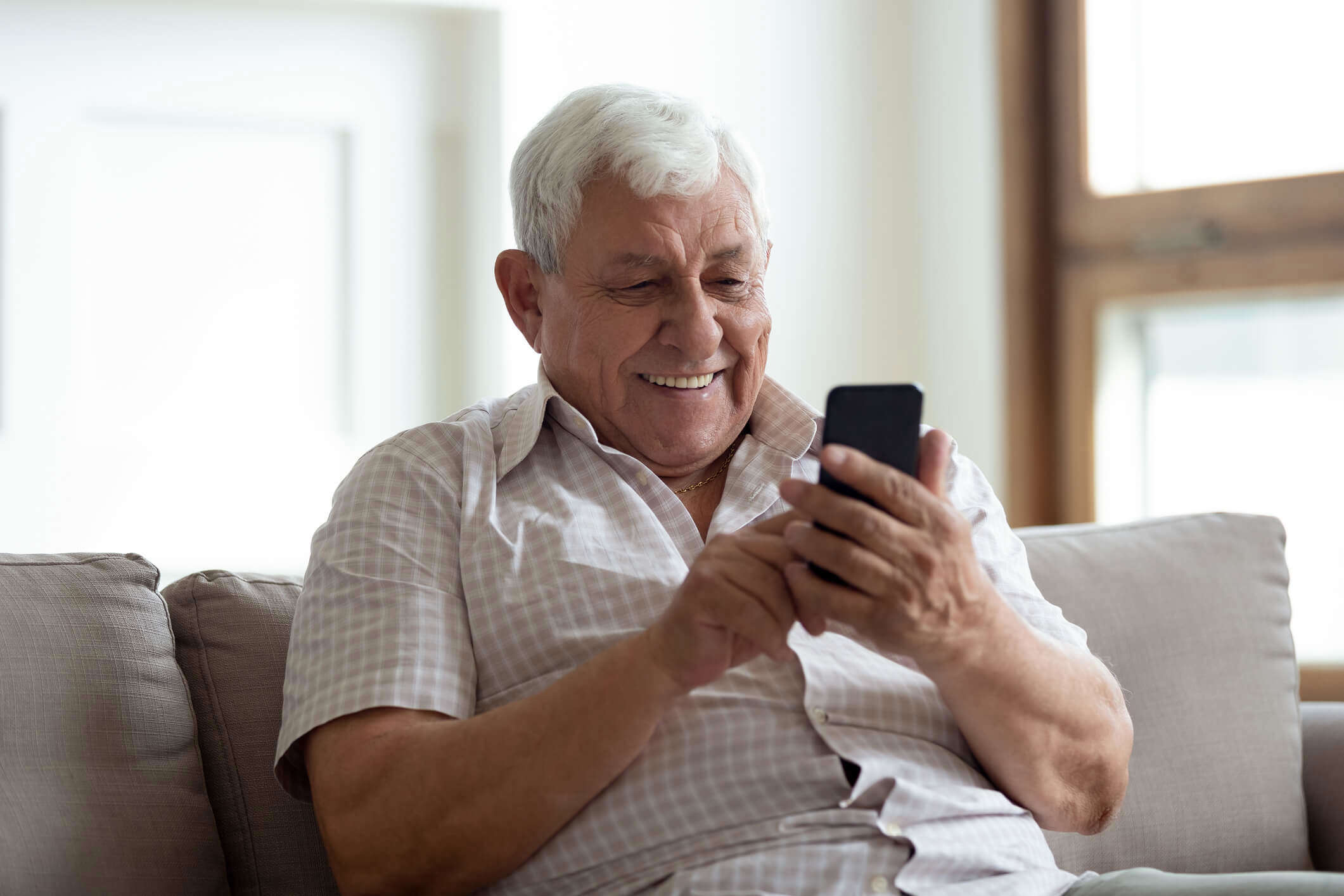 a older man looking at his phone and smiling