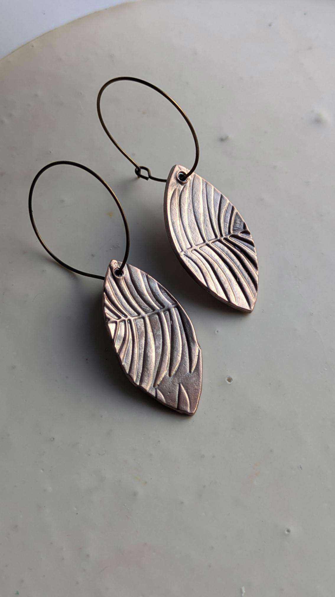 Main image: handmade copper clay earrings, with large hoops, and a leaf print design.